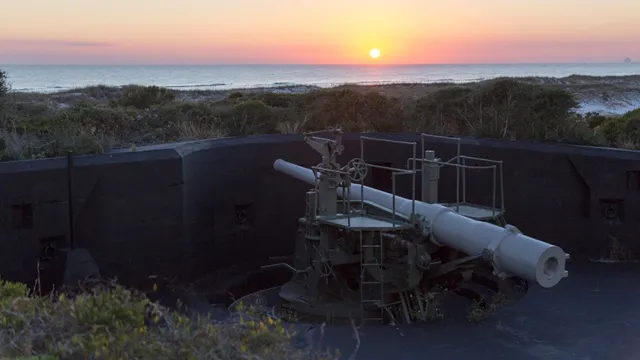 The sunsets over the water, in the foreground a cannon is mounted. — Gulf Islands National Seashore, NPS